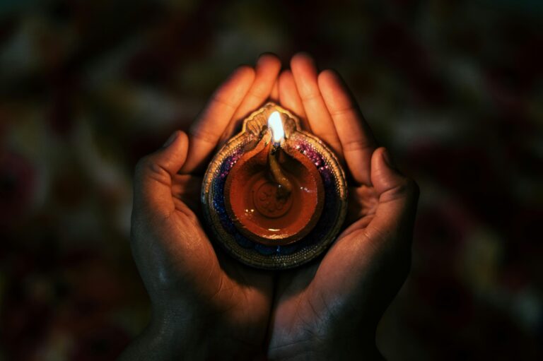 Top view of crop anonymous person demonstrating small bright candle burning in dark evening in soft focus