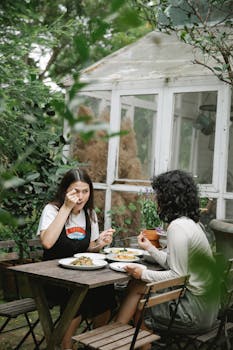 Female gardeners eating lunch at table in backyard