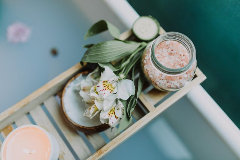 Spa essentials on a tray with Himalayan salt, flowers, and candles for a relaxing bath.