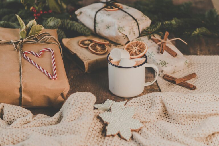 Warm and festive holiday scene featuring hot chocolate, wrapped gifts, cinnamon sticks, and knitted blankets.