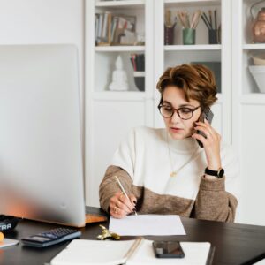 Focused businesswoman in modern office multitasking efficiently while on a phone call.