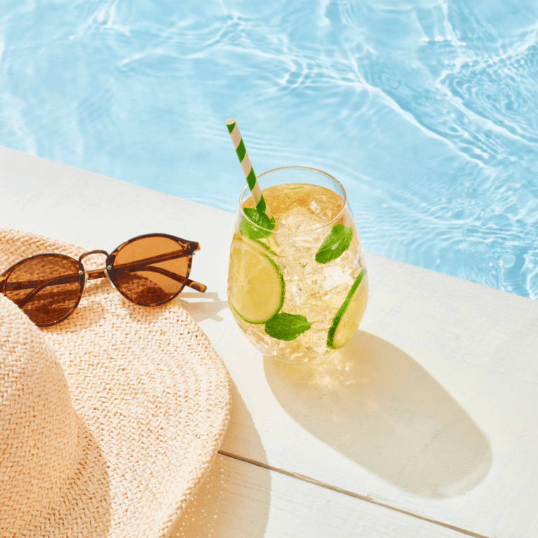 Cool drink, hat and sunglasses by the pool on a hot summers day
