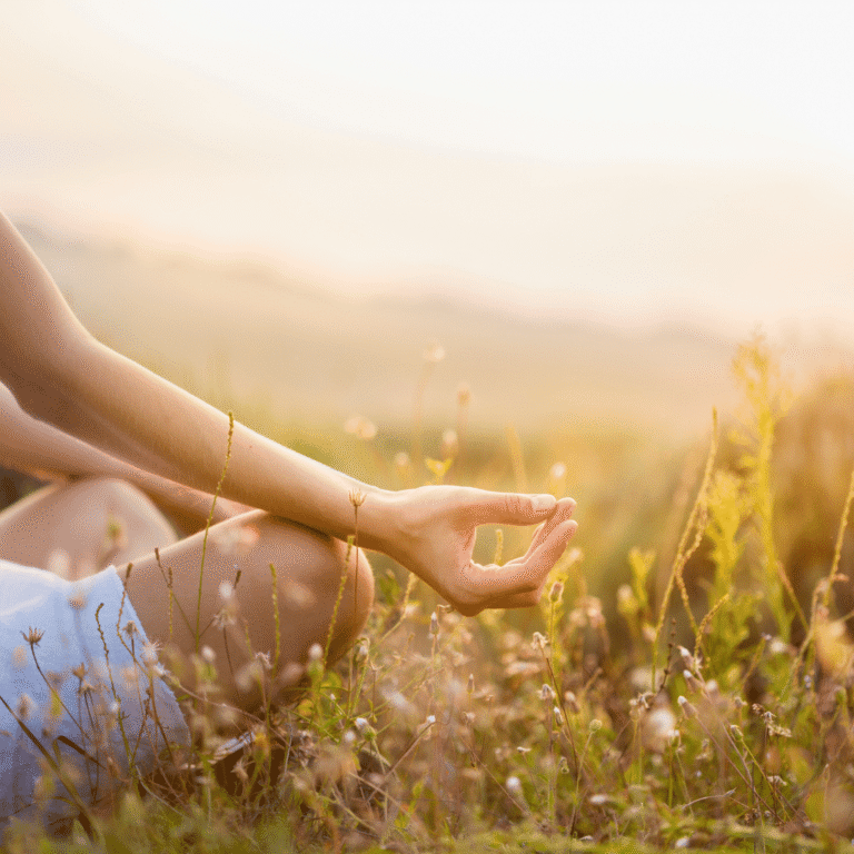 Woman meditating in nature in middle of summer meadow